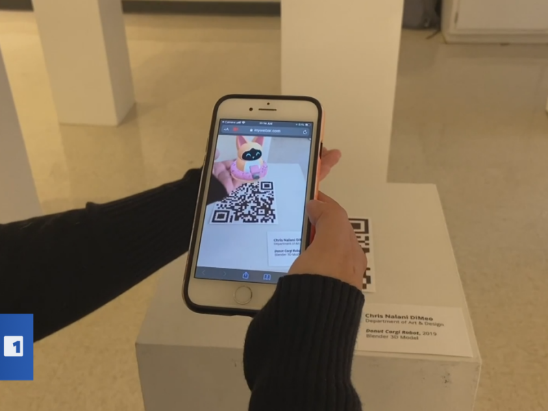 Hands holding a phone showing an augmented reality scene of a 3d model of a robot